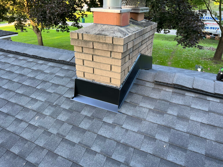 A detailed view of custom chimney flashing installation with inset design and corner extensions, paired with Timberline Ultra HDz Charcoal shingles by The Exterior Zone in Lapeer, Michigan.